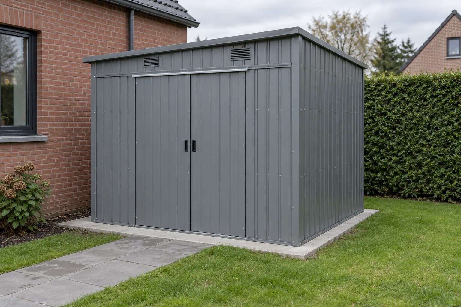Abri métallique gris à panneaux nervurés, portes coulissantes et grilles de ventilation