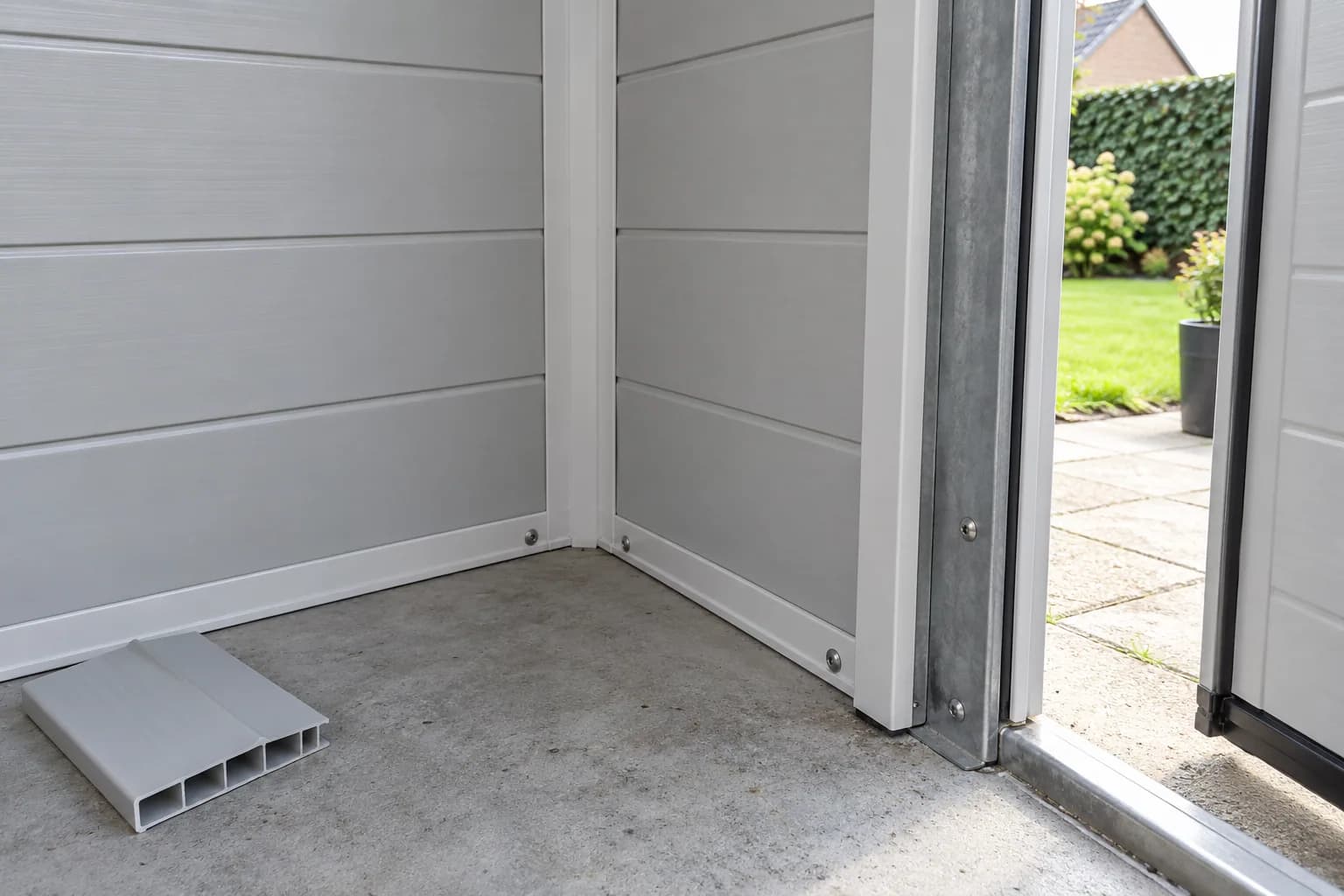 Panneaux en PVC, montant métallique de porte et chute alvéolaire sur la dalle d’un abri