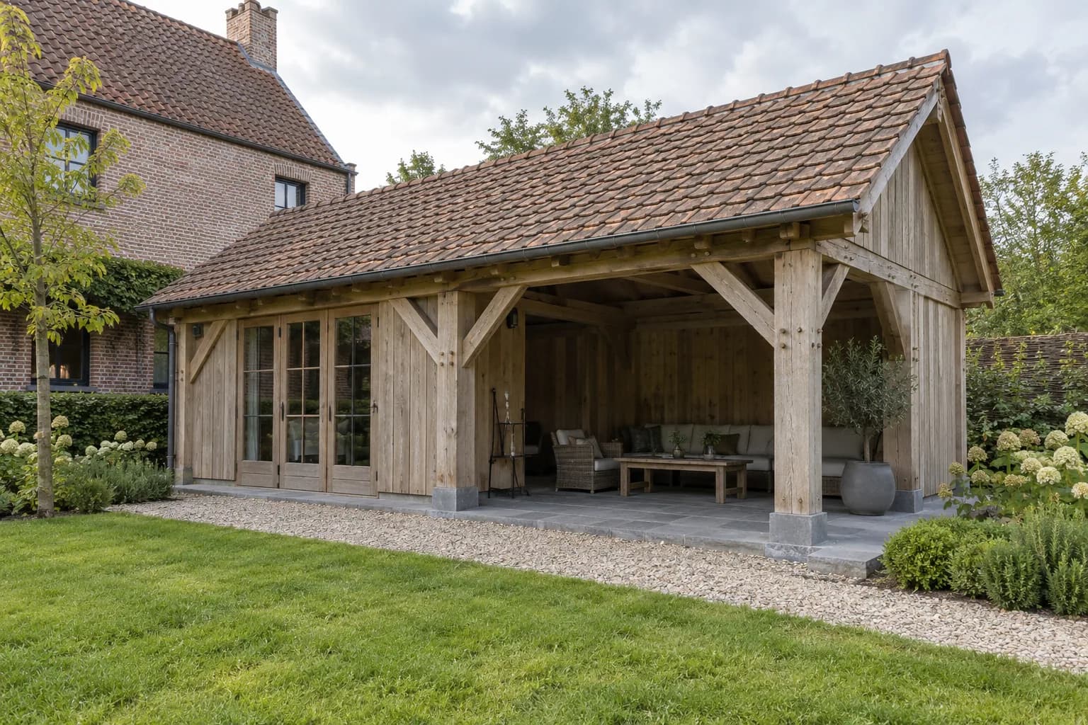 Annexe à charpente en chêne, toit en tuiles et terrasse couverte sur des socles en pierre bleue.