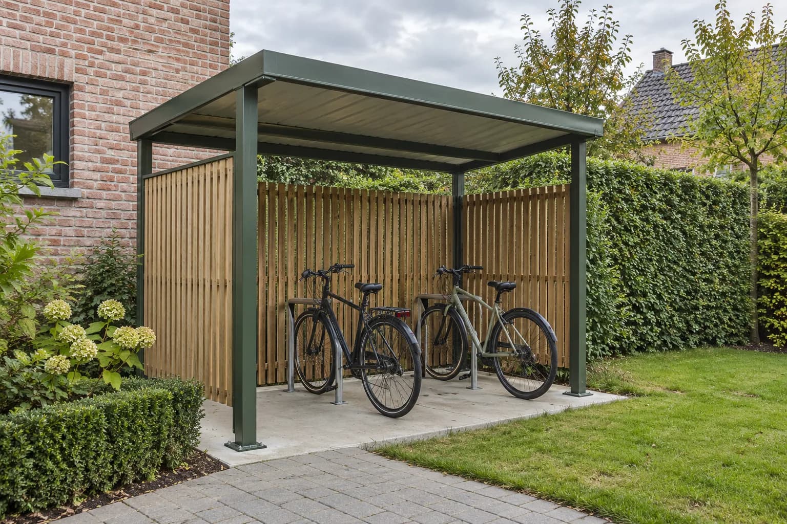 Abri pour deux vélos avec poteaux verts, toit métallique et parois à lattes de bois près d'une maison.