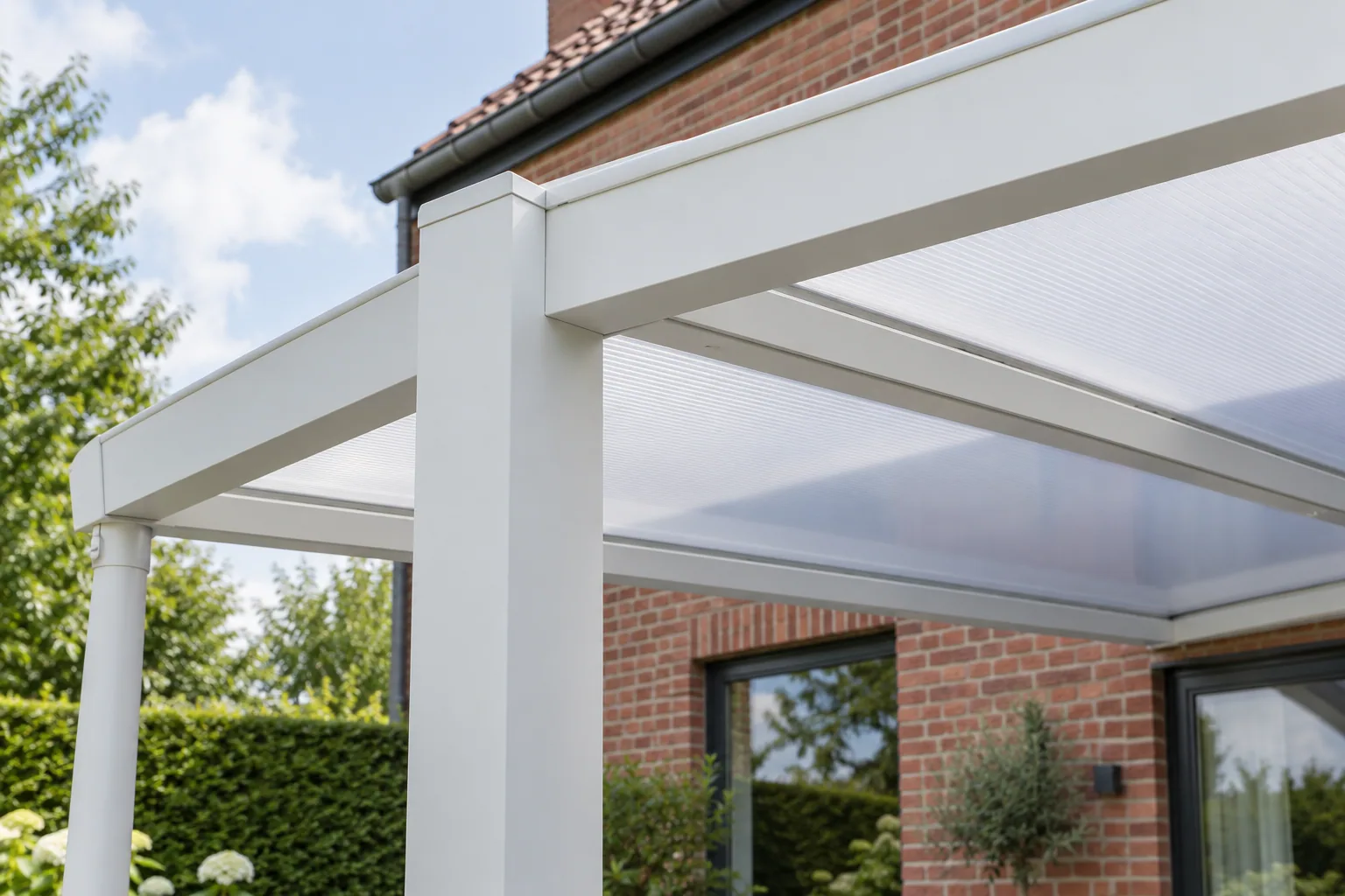 Profilés blancs et panneaux de toiture alvéolaires à l’angle d’un carport en aluminium
