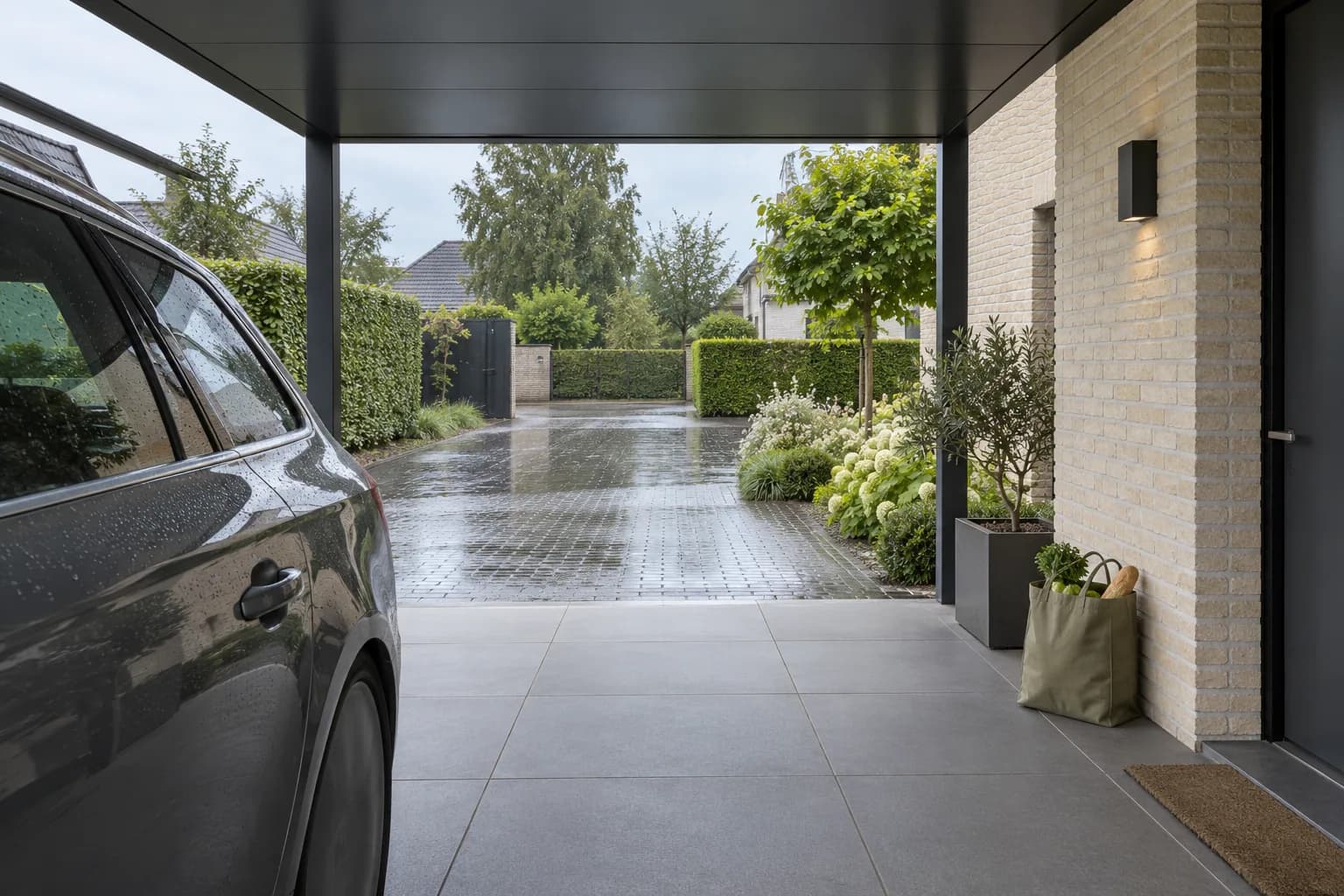 Accès sec à la maison sous un carport à toit plat, avec voiture garée et sac de courses près de la porte