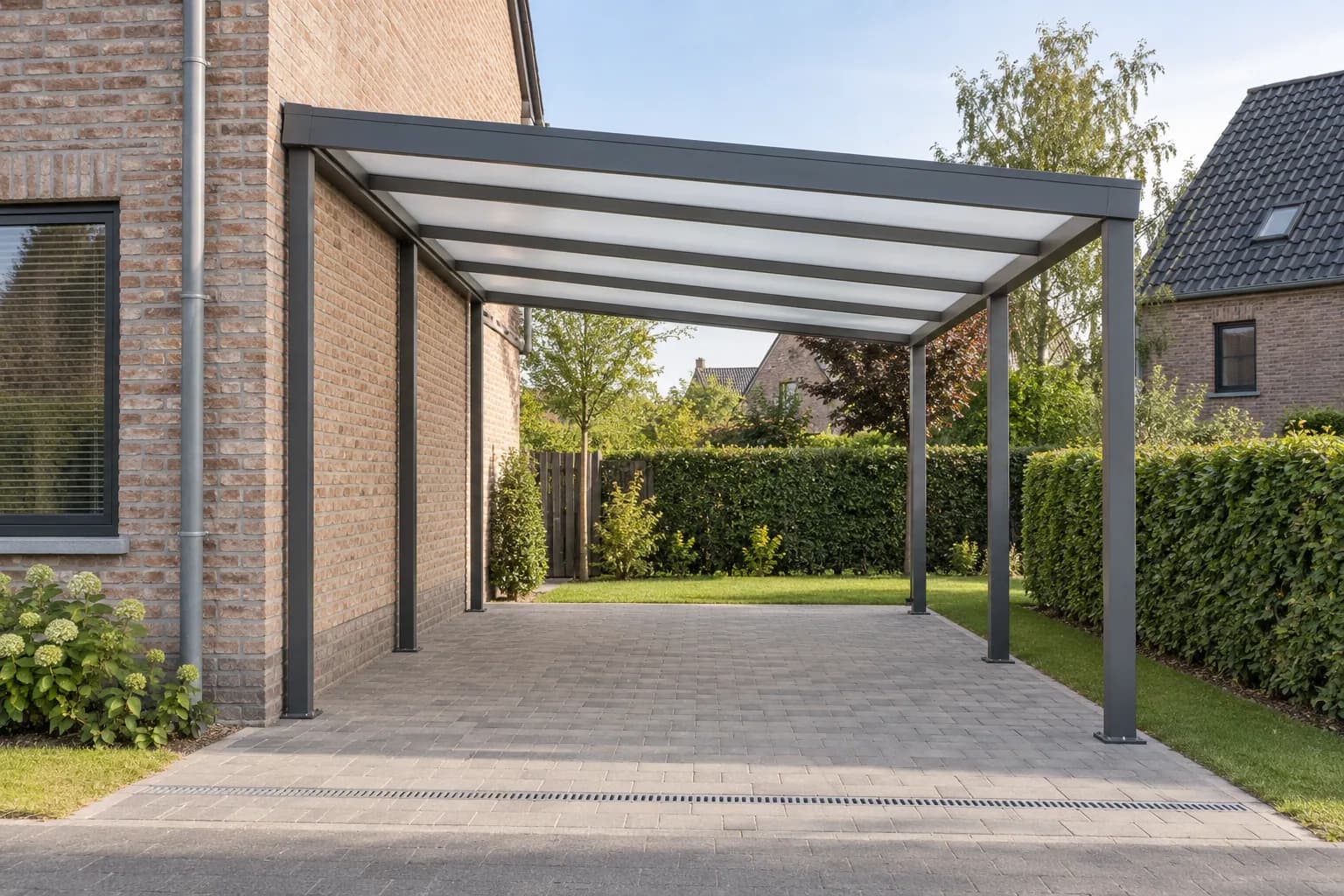 Carport gris à couverture translucide sur six poteaux, installé sur une allée pavée près d’une maison
