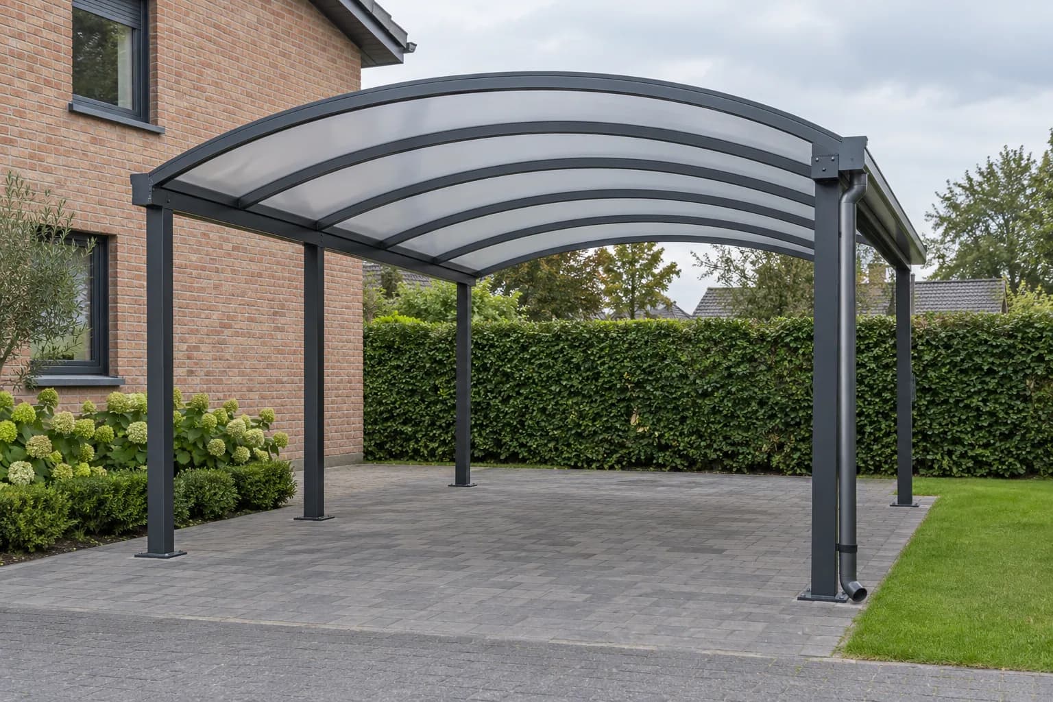 Carport en aluminium anthracite avec toiture translucide arrondie et descente d'eau latérale.