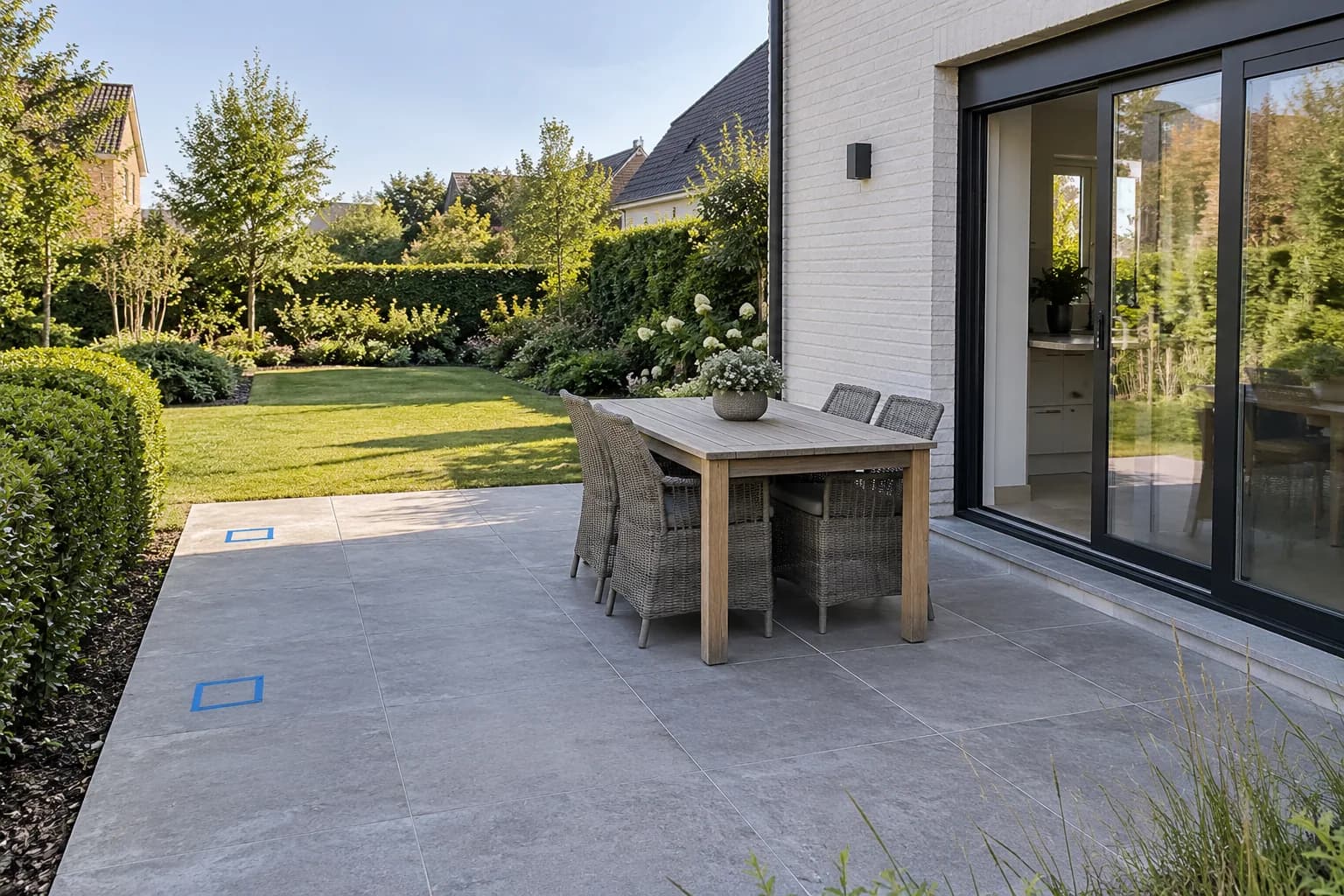 Deux emplacements de poteaux marqués au ruban bleu sur une terrasse, à distance de la table et des chaises.