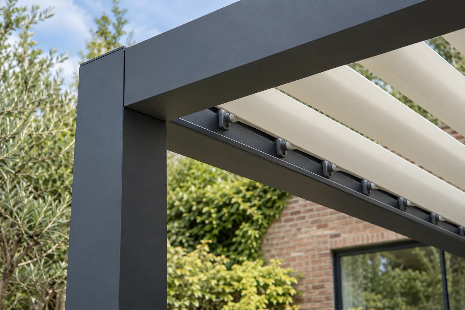 Assemblage d'un poteau et des poutres de pergola avec pivots de lames orientables claires.