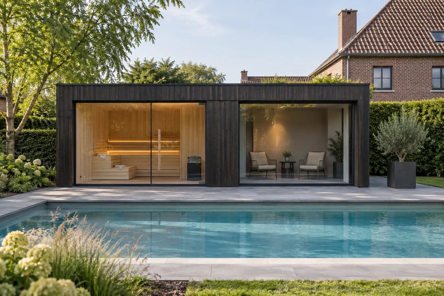 Pool house sombre avec sauna vitré et espace de repos séparé, devant une piscine dans un jardin belge.