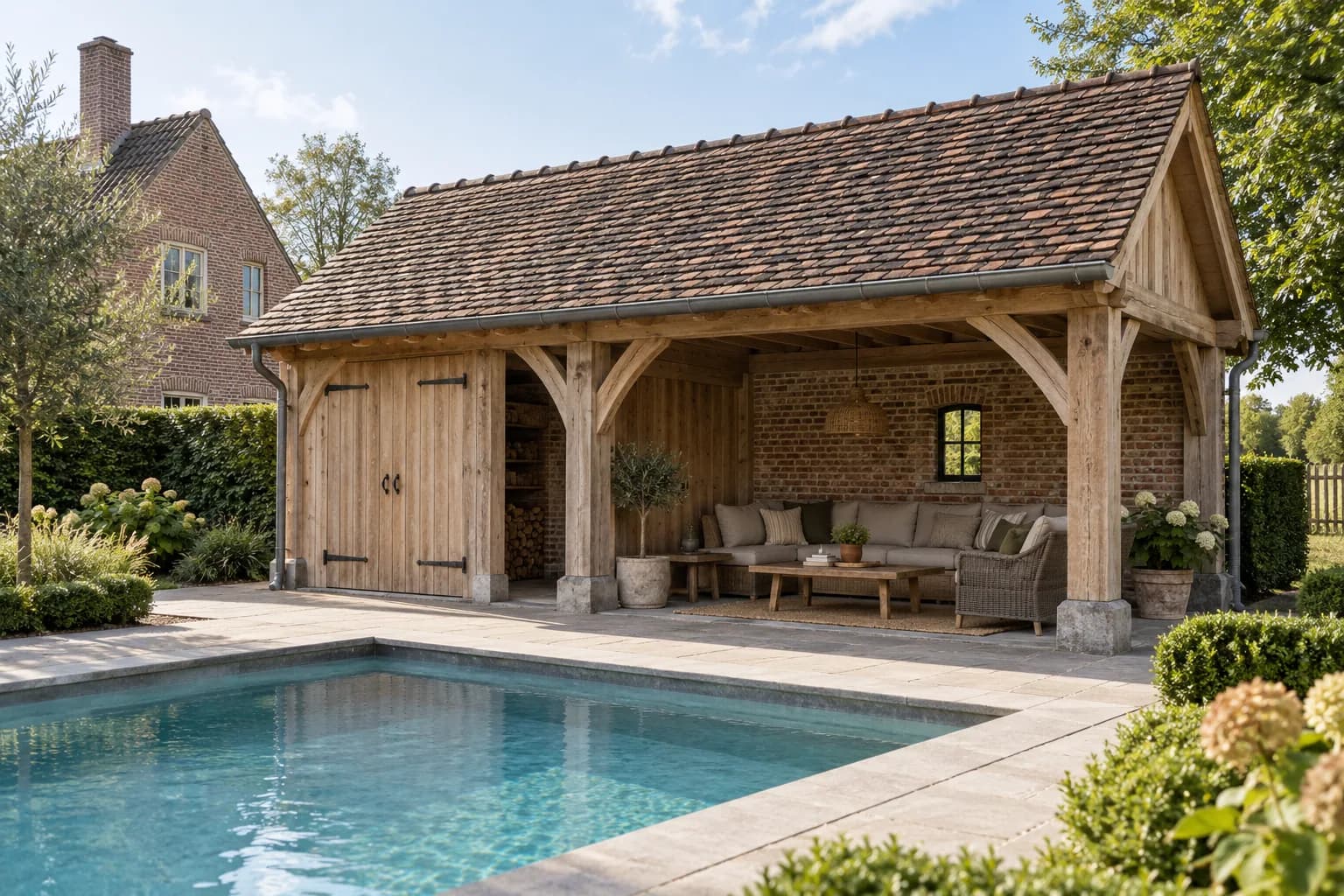 Pool house à charpente en chêne sur dés de pierre, avec toit de tuiles et salon ouvert près de la piscine.