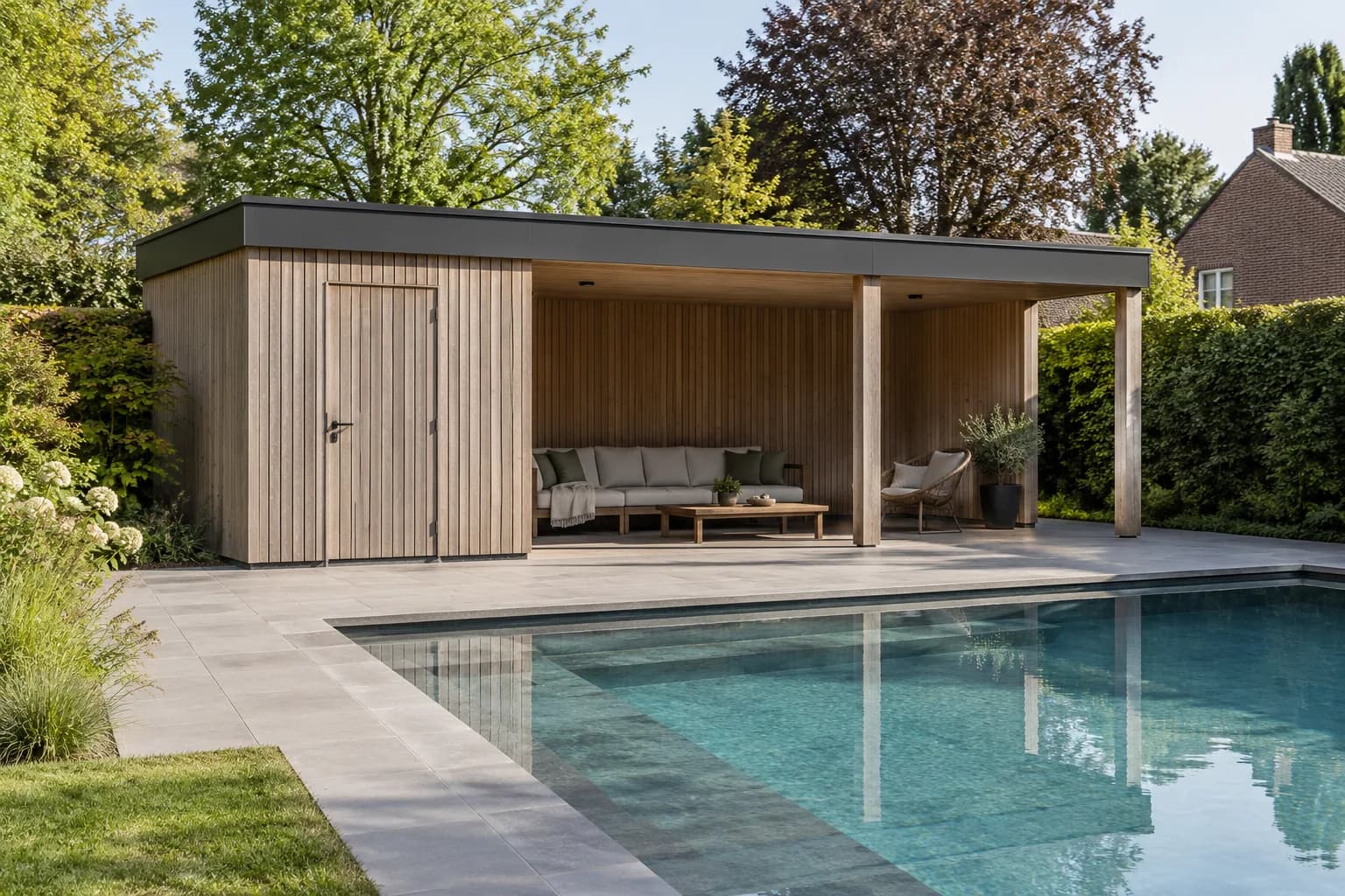 Pool house à bardage bois avec local fermé et salon couvert, au bord d’une piscine dans un jardin belge.