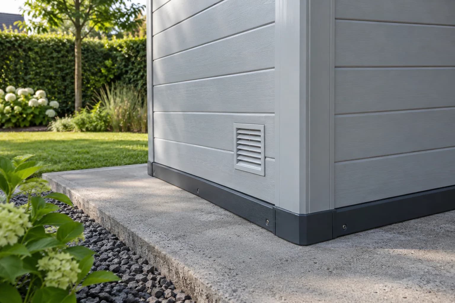 Jonction de panneaux plastiques et profilé d’angle, avec grille d’aération et rail de base sur dalle béton.
