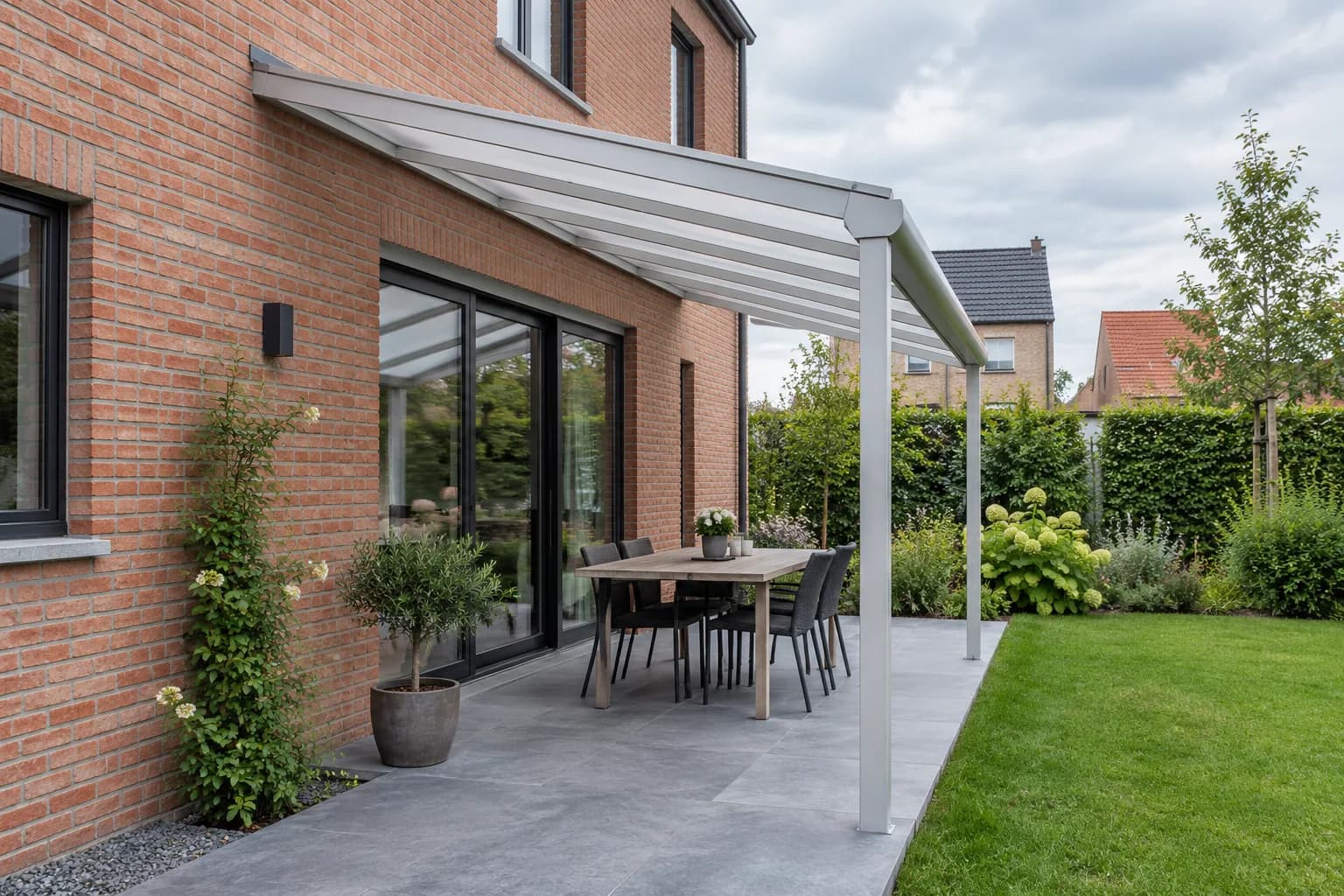 Toiture de terrasse à pente unique fixée contre une façade en briques et portée par deux poteaux à l’avant.