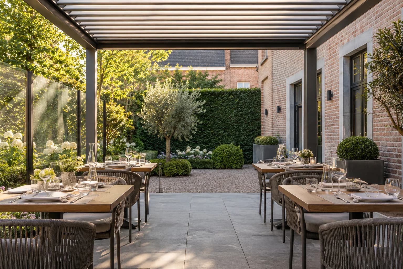 Tables dressées de part et d’autre d’un passage libre sous la toiture à lames d’une terrasse de restaurant.