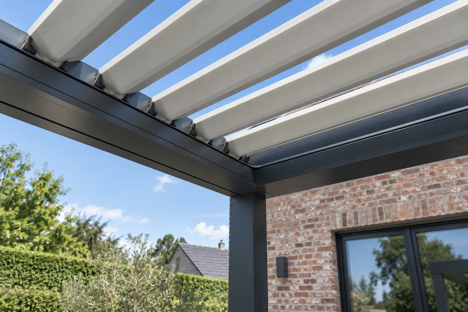 Lames blanches inclinées et leurs fixations dans l’angle du cadre anthracite d’une pergola.