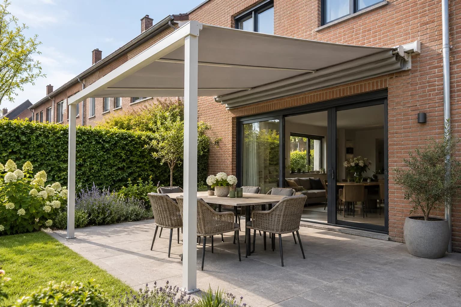 Toile rétractable sur une structure blanche couvrant une table devant une maison en briques.
