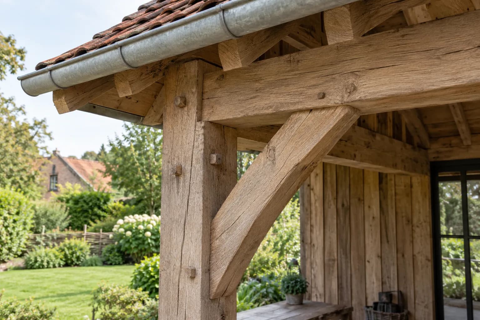 Detail van een houten staander, ligger en diagonale schoor onder een pannendak met zinken goot