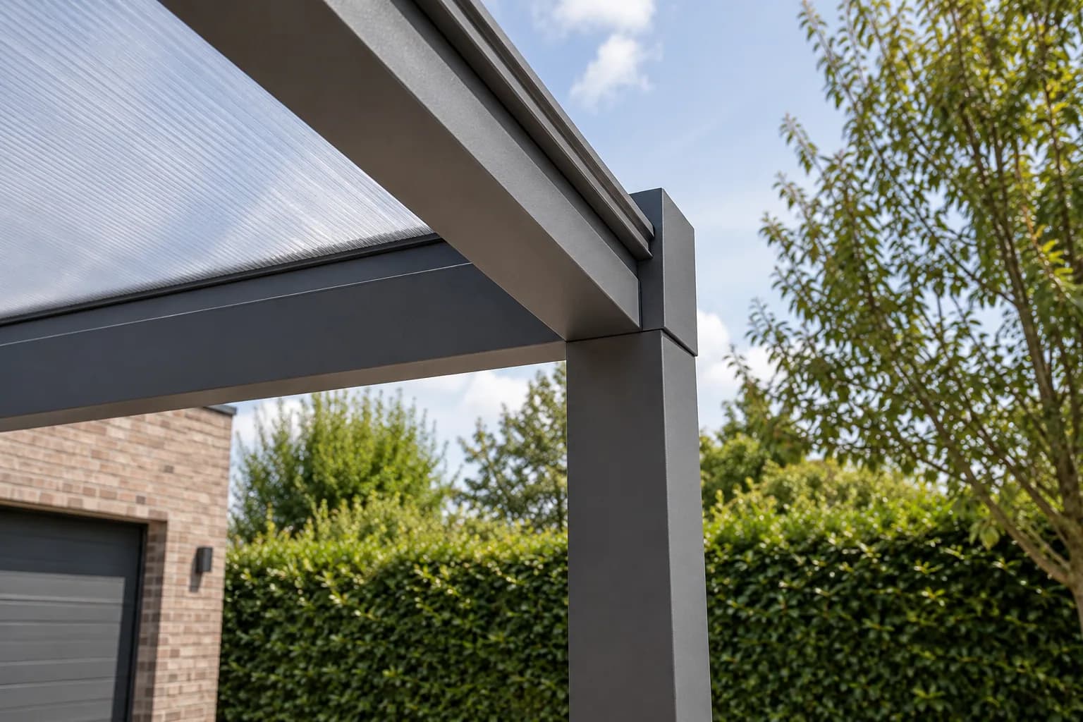 Donkere aluminium dakbalk en staander onder de lichtdoorlatende panelen van een carport.