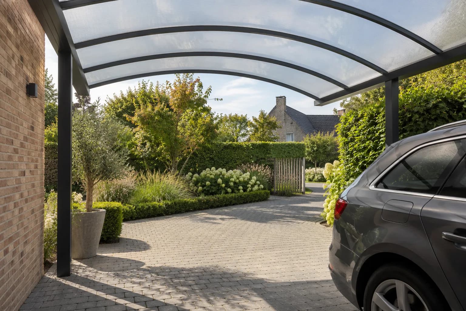 Binnenaanzicht van een carport met gebogen lichtdoorlatend dak en vrije ruimte naast de auto.