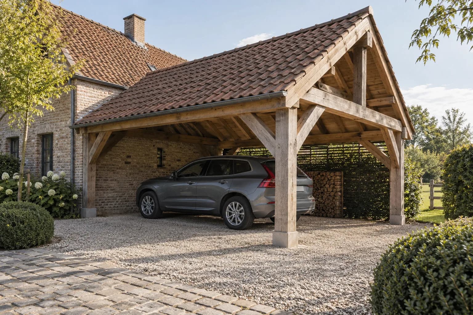 Landelijke eiken carport met pannendak en houten schoren op een oprit bij een bakstenen woning.