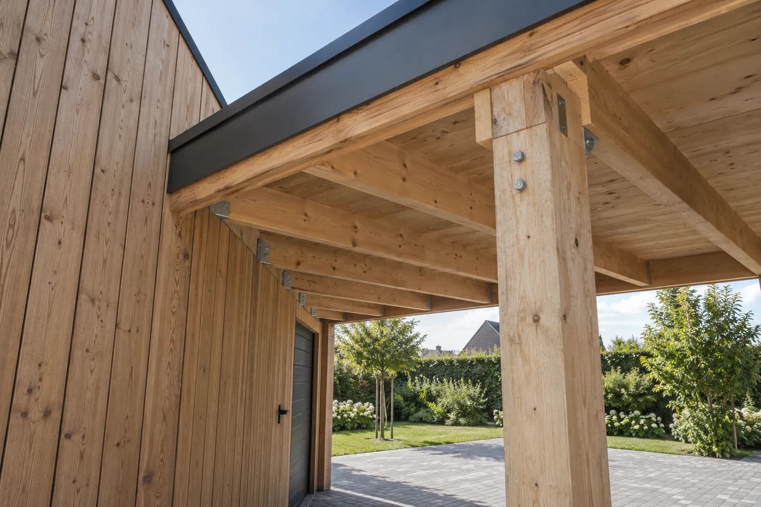 Houten carportdak met balken, metalen bevestigingen en een draagpaal naast de gesloten garage.