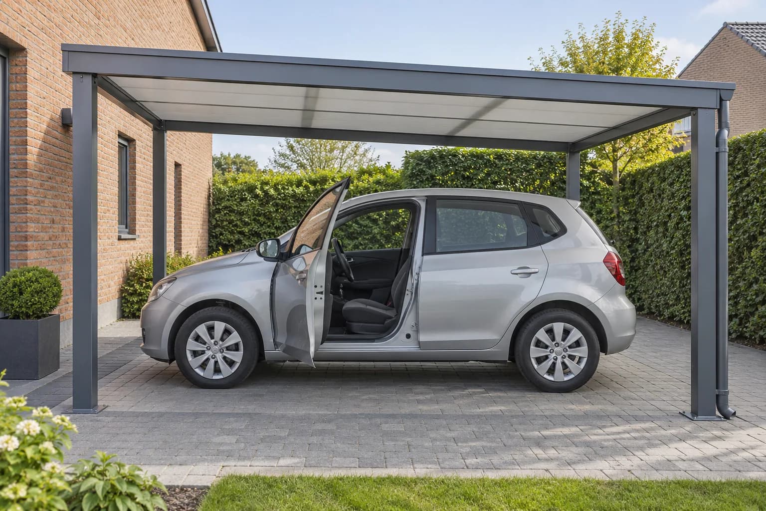 Zilveren auto met geopend portier onder een grijze carport met vrije uitstapruimte en regenafvoer