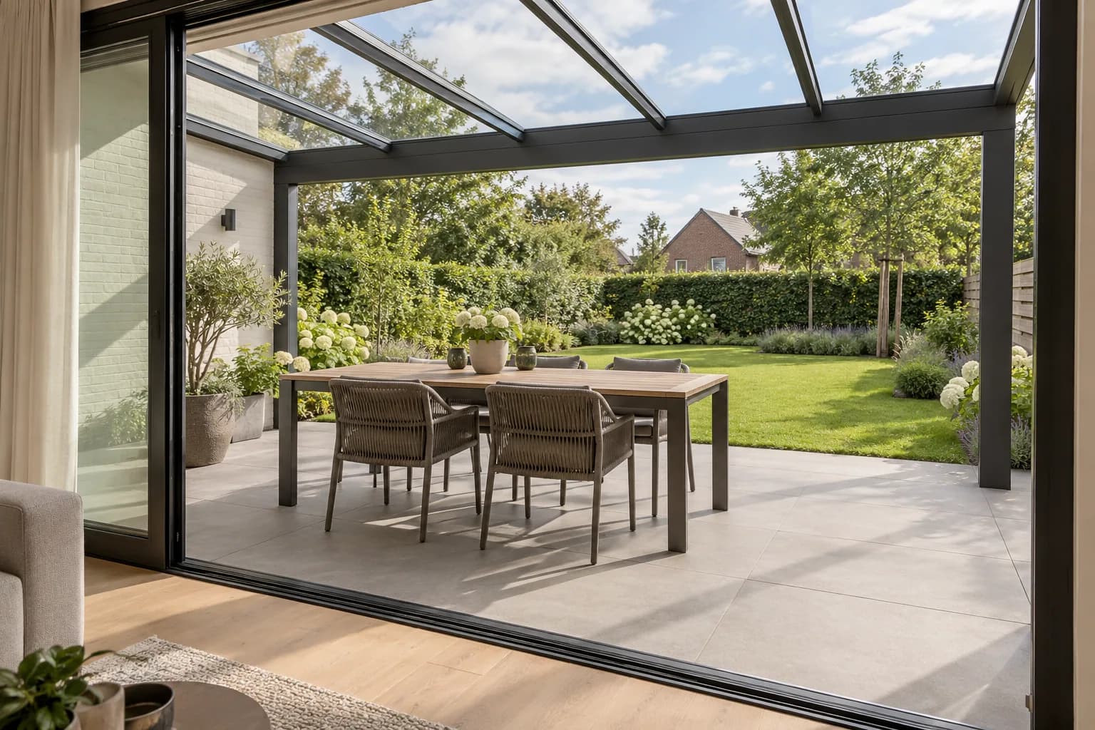 Doorgang vanuit de woning naar een overdekt terras met eettafel en zicht op de tuin.