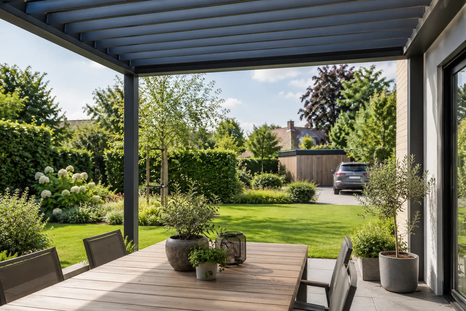 Eethoek onder een aluminium terrasoverkapping met open uitzicht op de tuin.