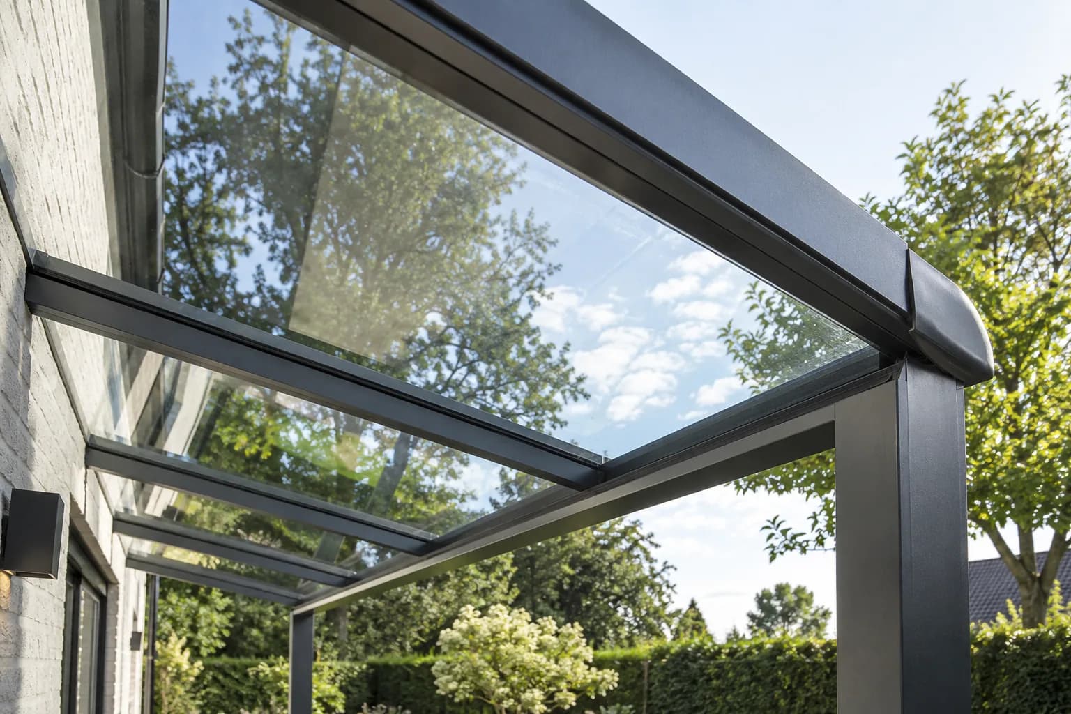 Glazen dakplaat met aluminium glasprofiel en dakrand van een terrasoverkapping.