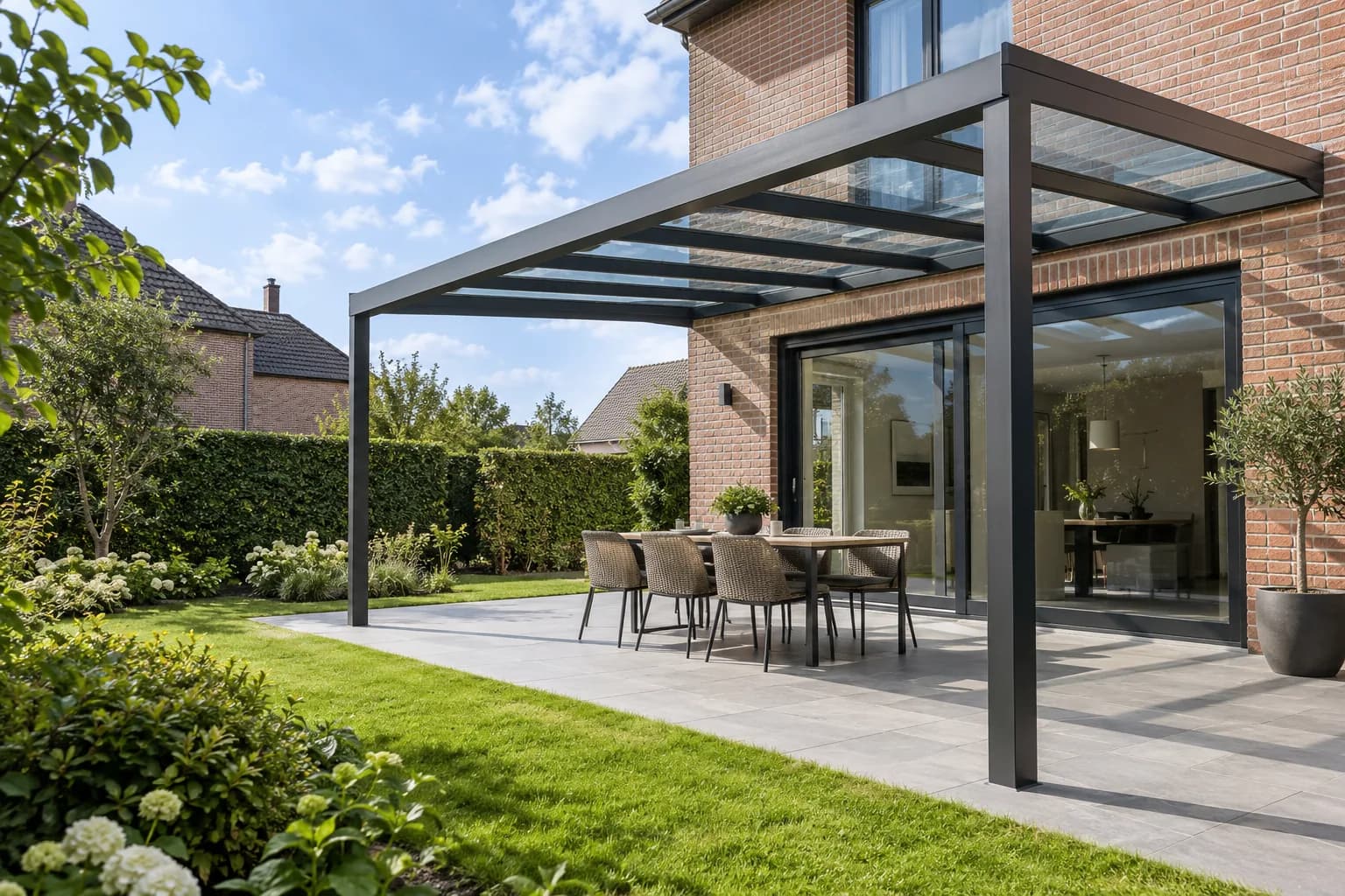 Glazen terrasoverkapping met aluminium draagstructuur en open zijden aan een woning.