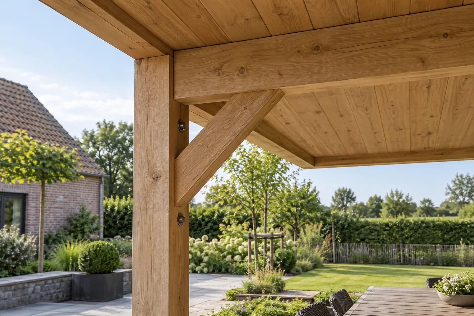 Detail van houten staander, dakbalk en schuine schoor van een terrasoverkapping.