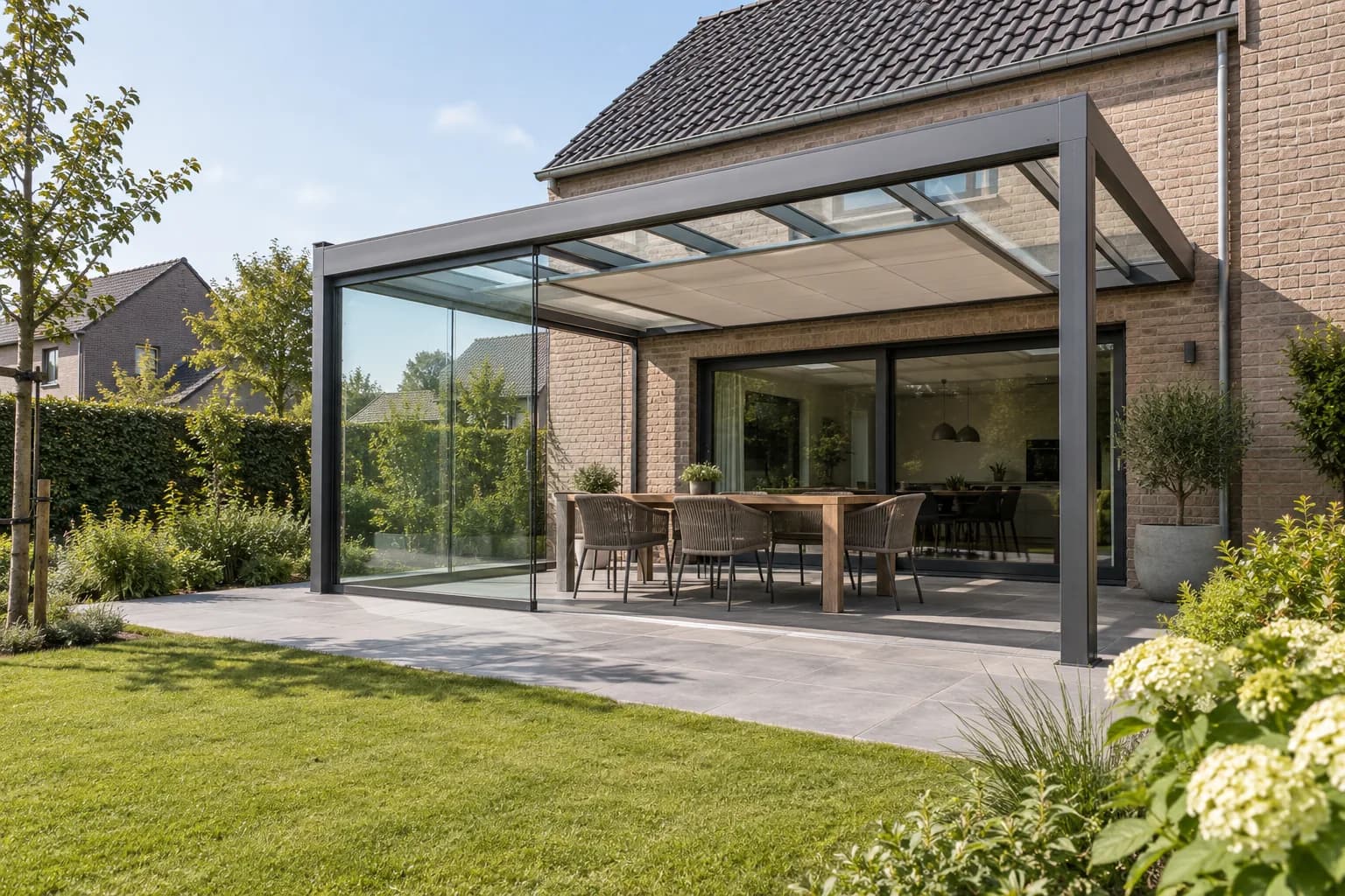 Terrasoverkapping met glazen zijwand en zonwering als aanvullende uitvoeringskeuzes.