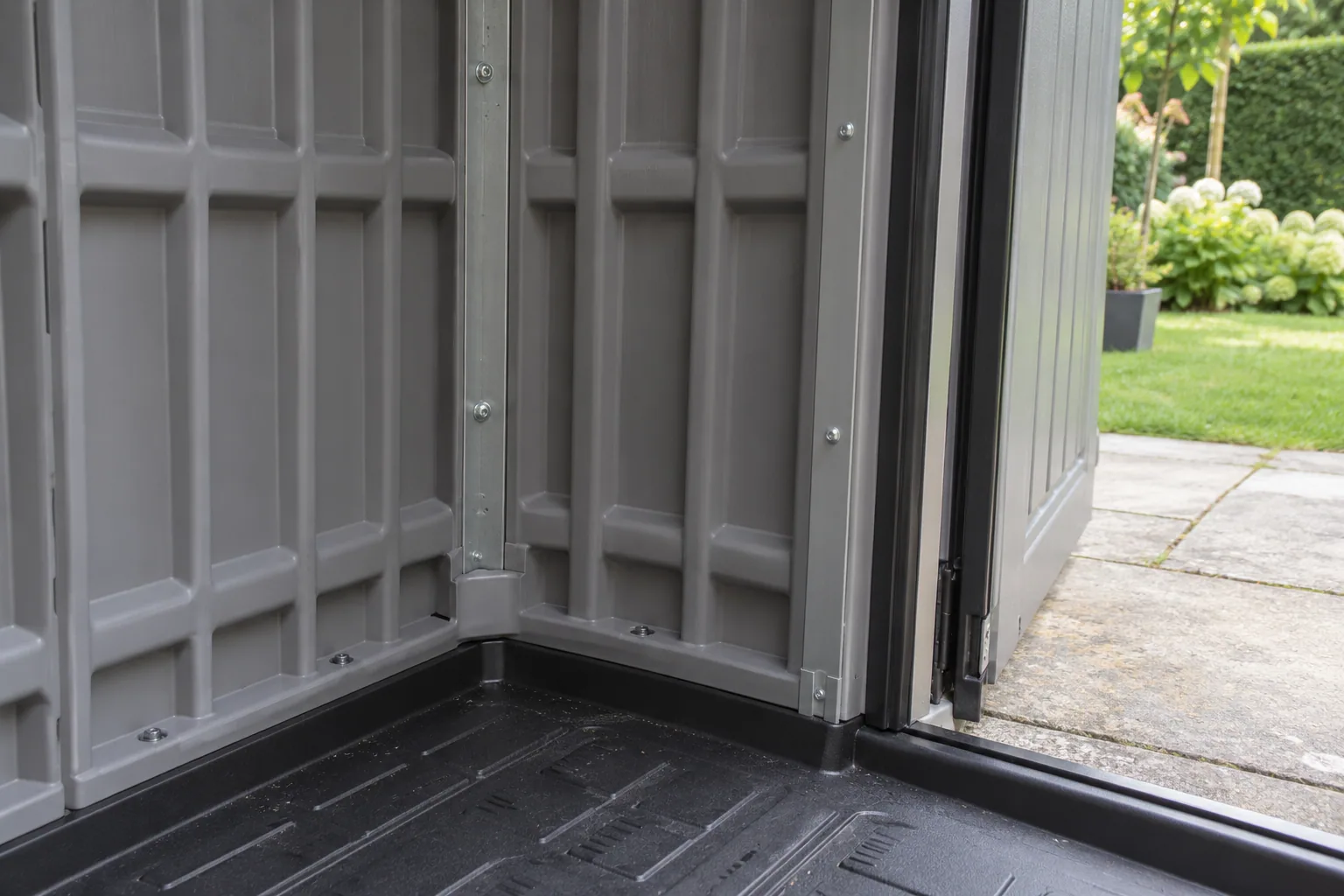 Geribde kunststof wandpanelen met metalen versteviging en een zwarte vloer bij de deurdrempel.