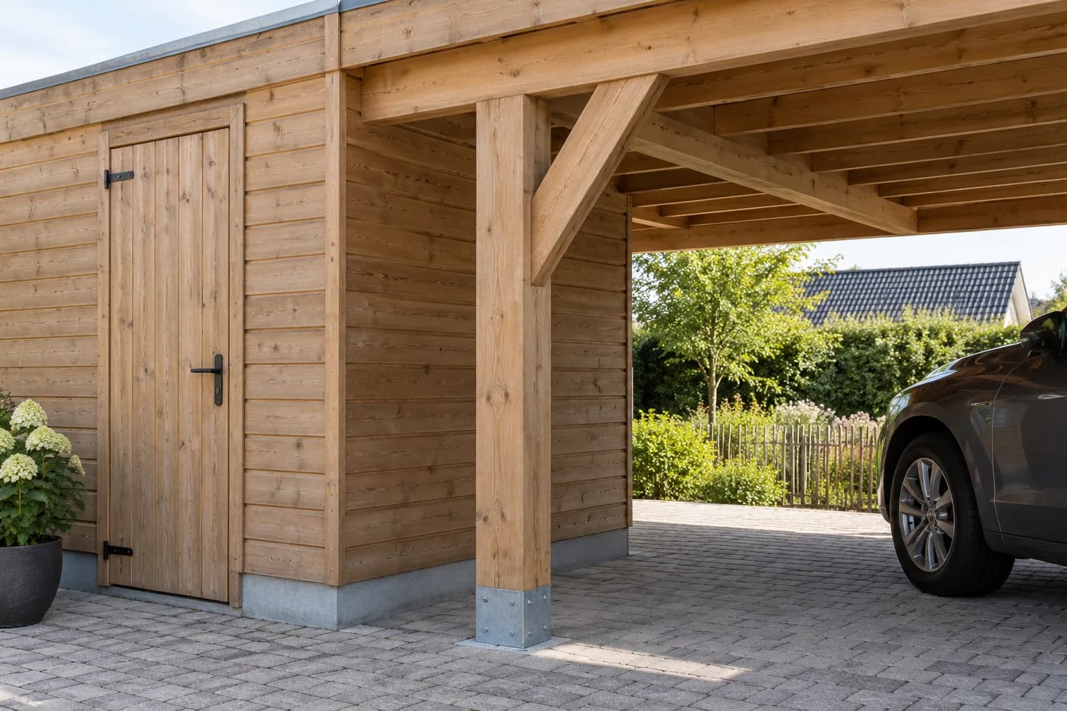 Houten draagbalk en geschraagde staander tussen tuinberging en carport.