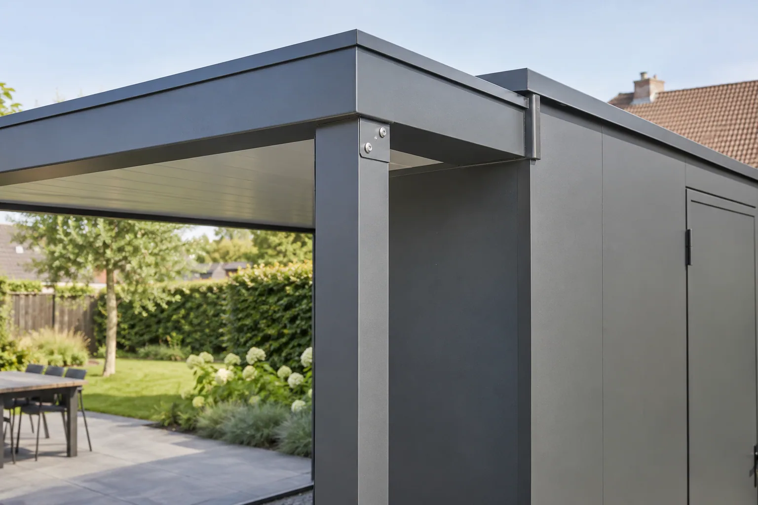 Aansluiting van een donkere aluminium staander op de dakbalk naast een tuinberging.