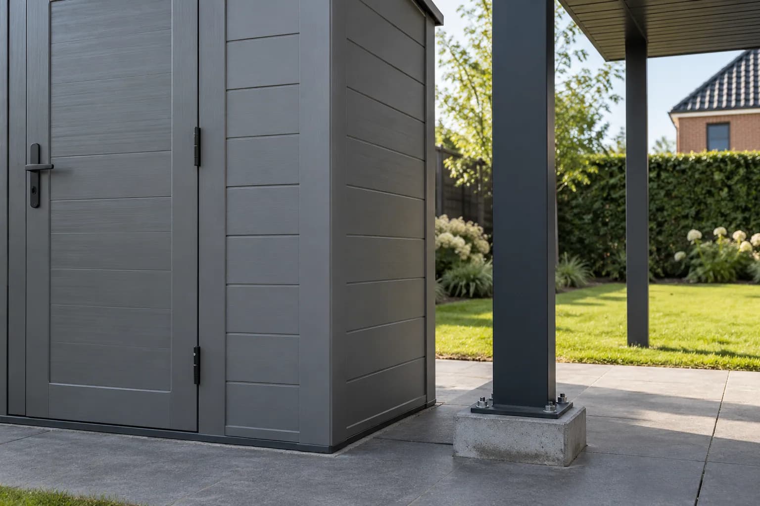 Kunststof wandpanelen van een tuinberging naast de vrijstaande metalen paal van een overkapping.