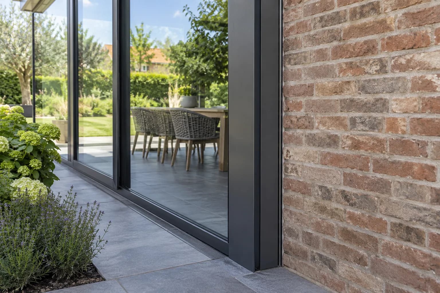 Aansluitdetail tussen het aluminium verandaprofiel en de bestaande bakstenen gevel.